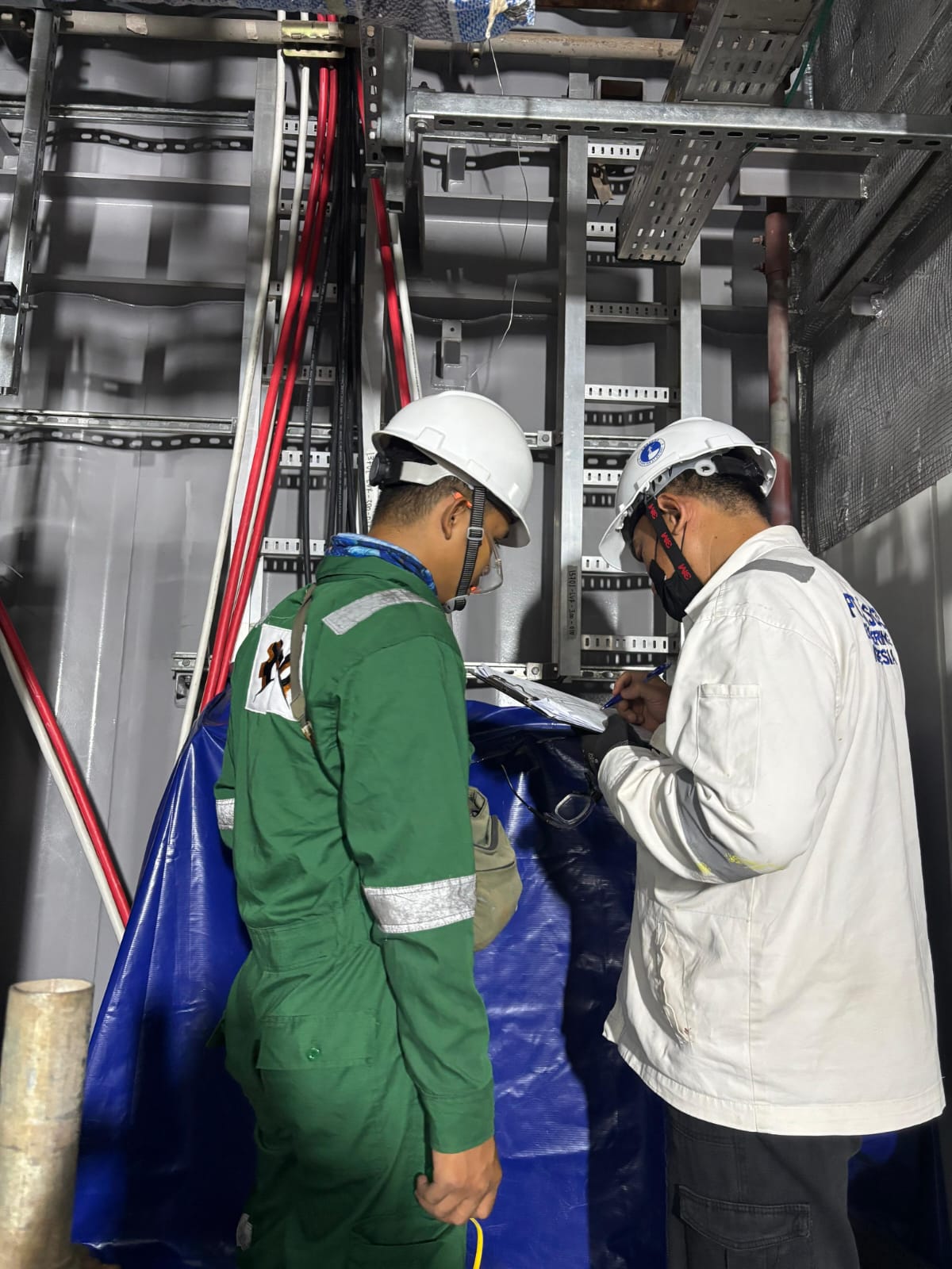 E&I technicians inspecting cable routing inside E-House module